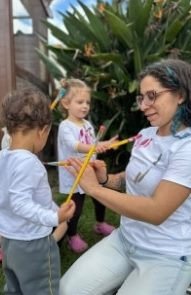 Educadora e crianças pintando ao ar livre no ateliê