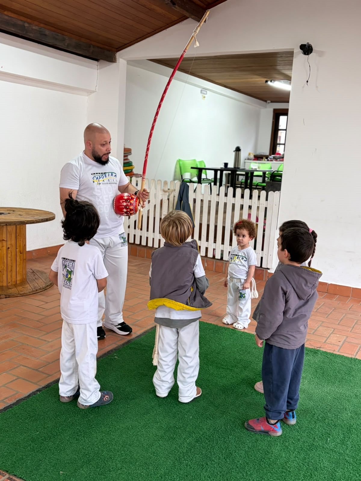 Professor de capoeira mostrando o berimbau para as crianças