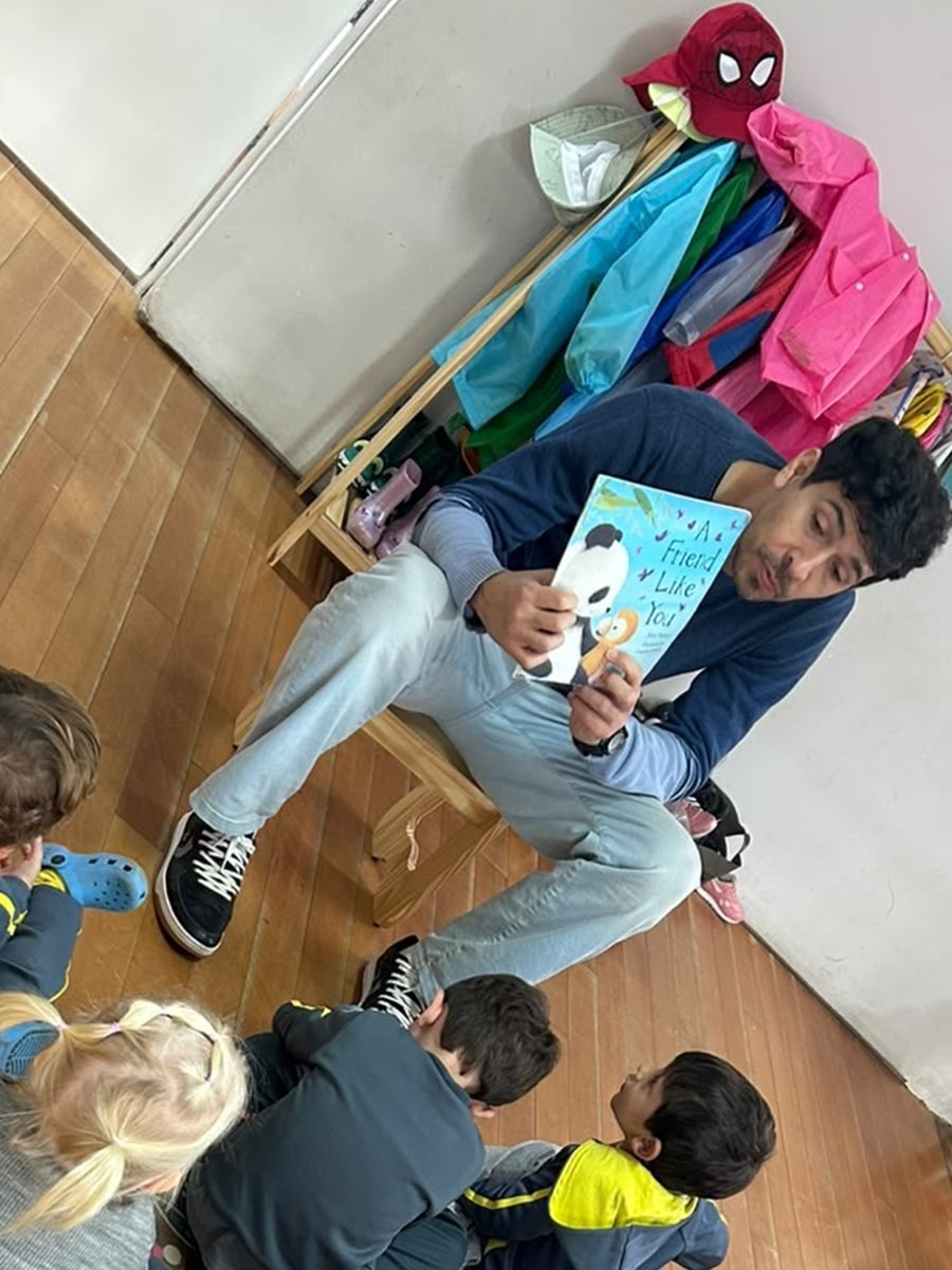 Professor lendo um livro em inglês para as crianças sentadas na roda