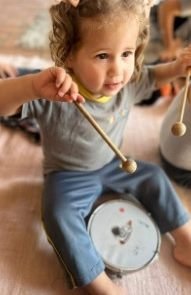 Criança tocando tambor na aula de musicalização