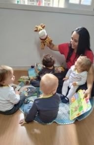 Educadora contando história com fantoche para os bebês