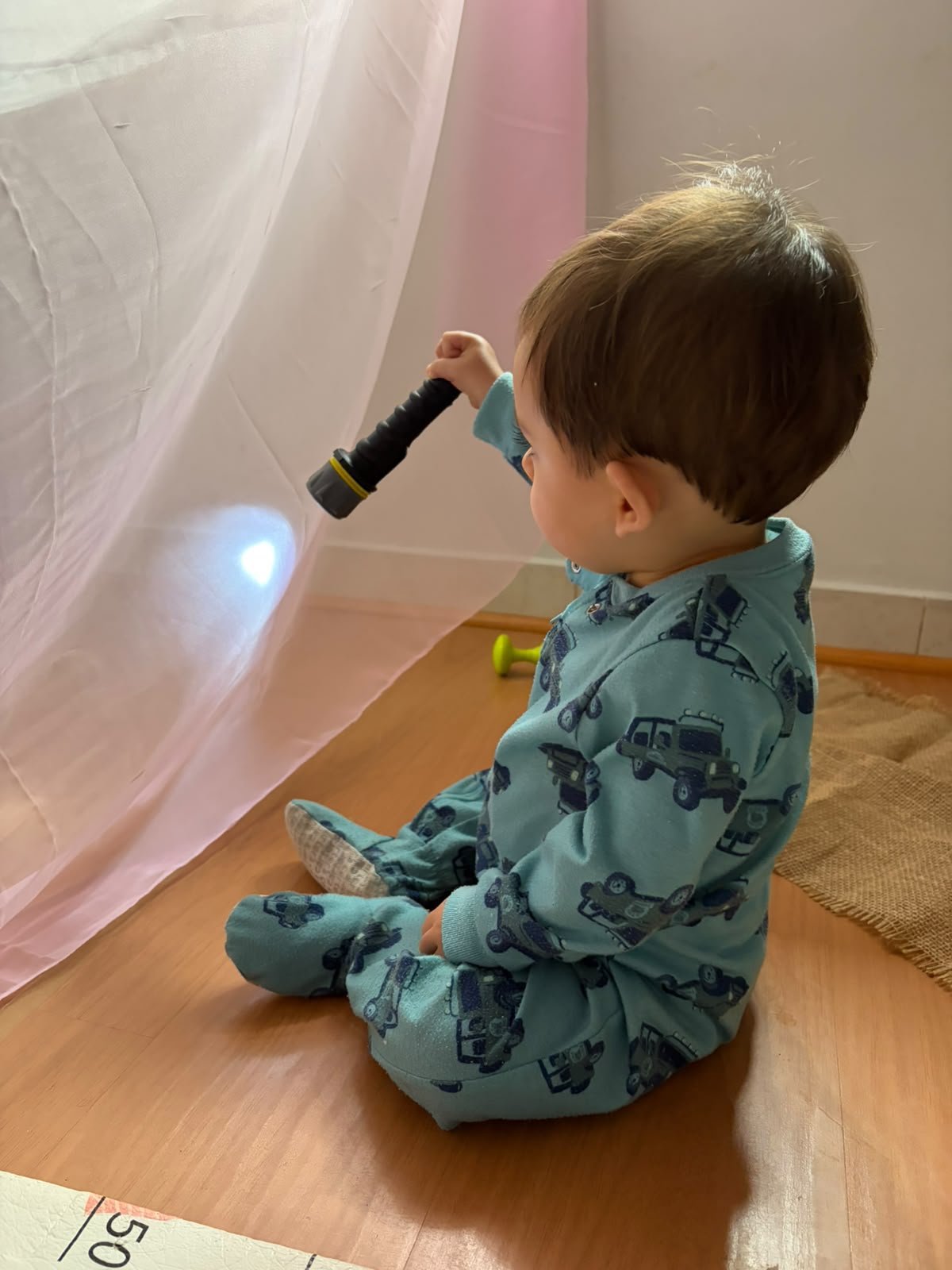Bebê explorando a luz de uma lanterna atrás de um tecido