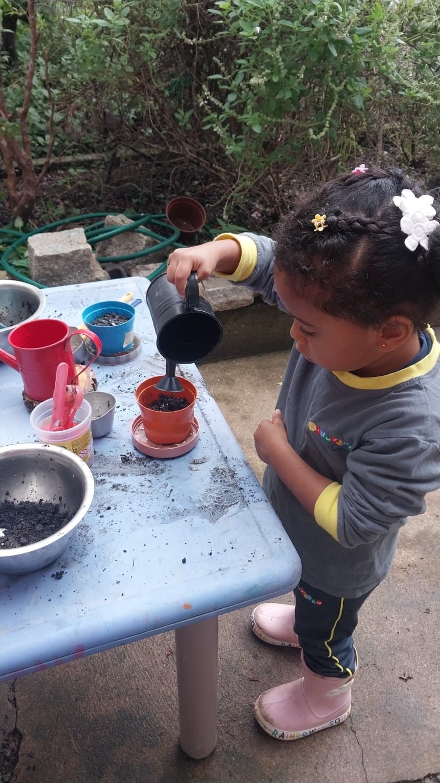 Menina regando um vasinho de terra